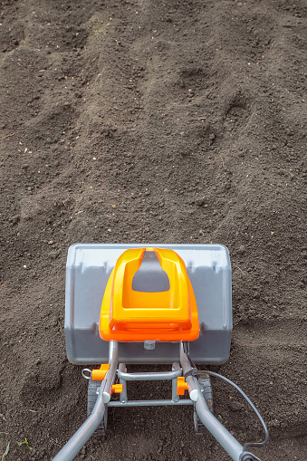 Electric cultivator cultivates soil in vegetable garden. Top view.