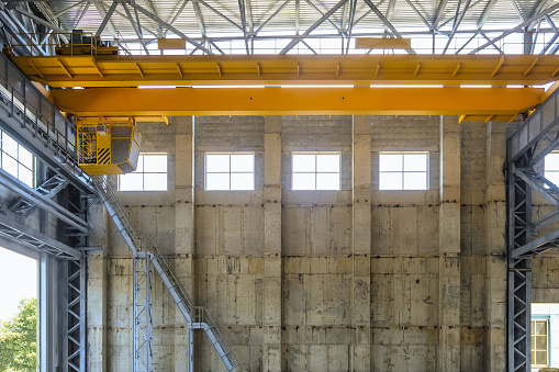 Yellow overhead crane on beam trestle in span of industrial building