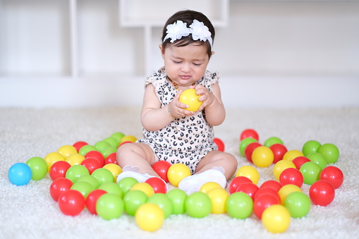 The baby girl playing with colored balls