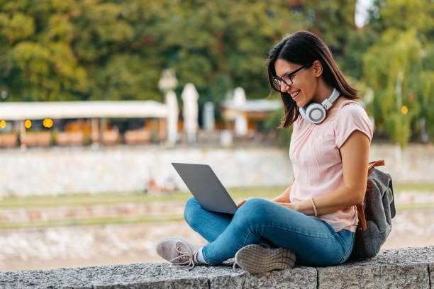 mujer joven trabajando en su computadora portátil en el muelle - river stones audio fotografías e imágenes de stock