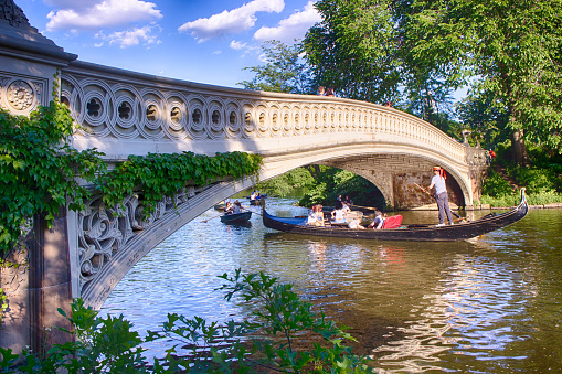 A Venitian gondola, complete with singing gondolier, passes under the ornate Bow Bridge in New York City's Central Park.