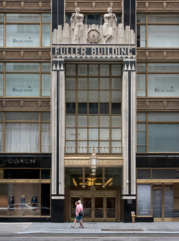 Two pedestrians walk by the 1929 Art Deco Fuller Building on E. 57th Street in Manhattan, New York City
