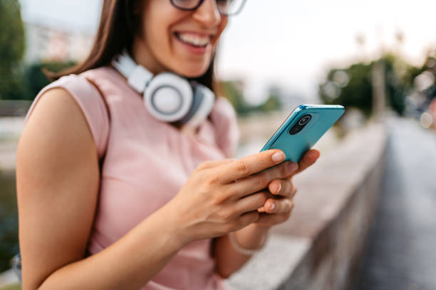 mujer joven usando un teléfono inteligente en el muelle - river stones audio fotografías e imágenes de stock