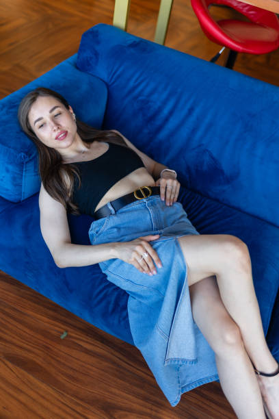 istock Young woman with bare legs poses for photo lying on sofa 1820805412
