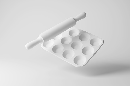White rolling pin and cupcake baking tray floating in mid air on white background in monochrome and minimalism. Illustration of the concept of bakery, bakeware and confectionery