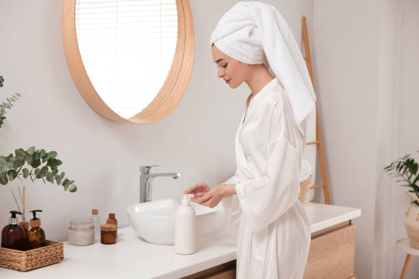 istock Beautiful young woman using body cream in bathroom, space for text 1820816390