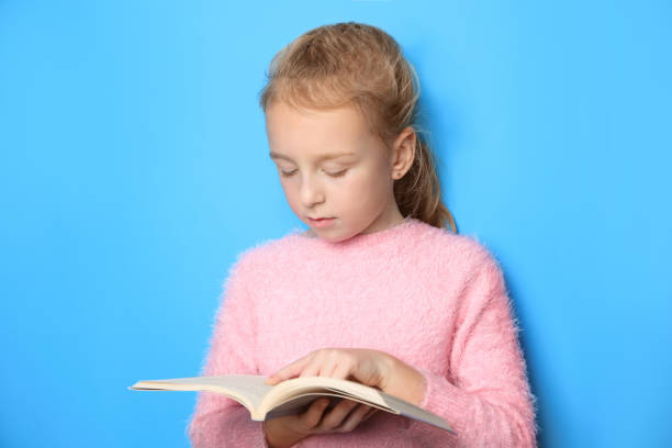 istock Little girl reading book on light blue background 1820816814