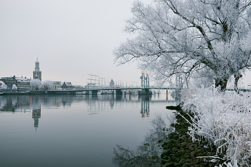 View on Kampen and river IJssel in winter in Holland. Kampen is an ancient Hanseatic League in Overijssel, The Netherlands. The New Tower and city bridge are  visible in the foreground of the city.
