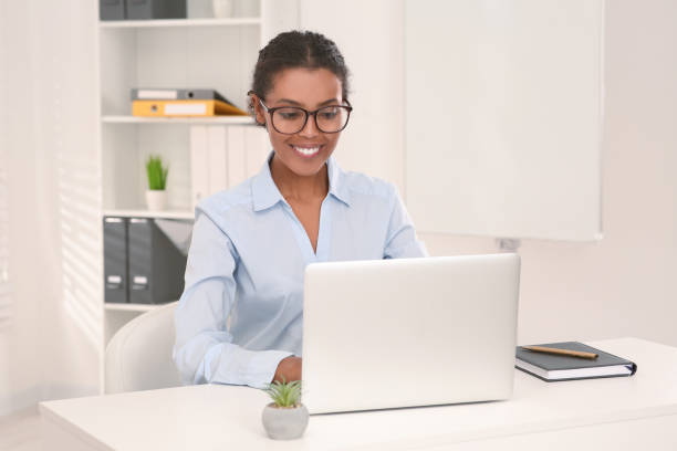 istock Smiling African American intern working on laptop at white table in office 1820831572