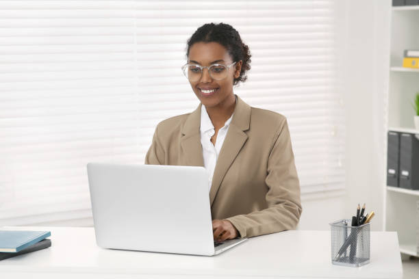 istock Smiling African American intern working on laptop at white table in office 1820831574