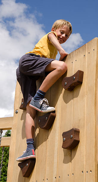 Boy on playground climbing wall stock photo