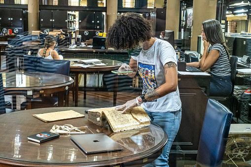 Rio de Janeiro, Brazil - Nov 29, 2023: Student digitizing old books with his mobile phone in the National Library in Rio de Janeiro, Brazil