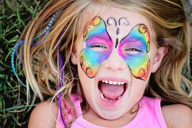 Butterfly Face Little girl with a painted butterfly on her face lying on the grass face paint stock pictures, royalty-free photos & images