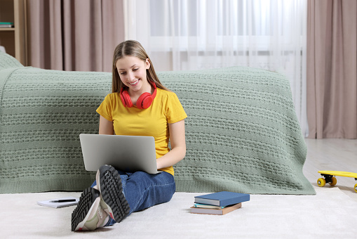Online learning. Teenage girl with laptop near bed at home