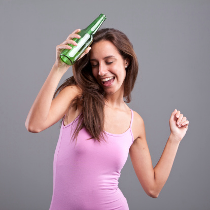 Happy girl dancing or staggering with a green bottle of beer