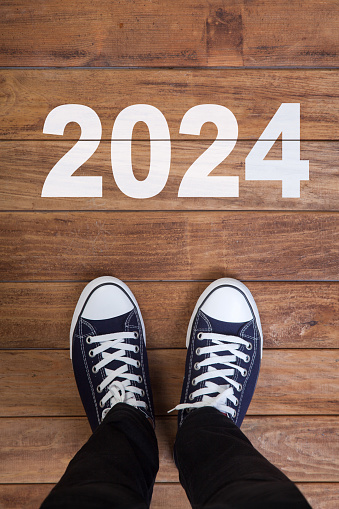 2024 written on wooden floor with man's feet