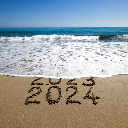 New year 2024 and old year 2023 written on sandy beach with waves