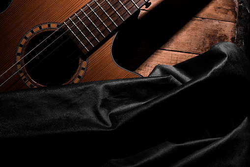 Classical guitar close up, dramatically lit on a black background with copy space