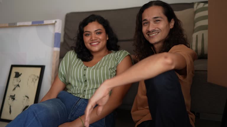 Portrait of a young couple talking sitting on ground at new house