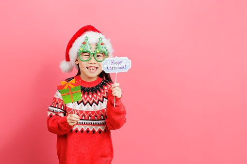 Medium shot of young Asian girl celebrating christmas against the plain background