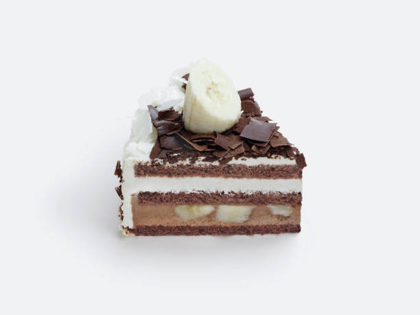 A sliced of chocolate cake with fresh cream and banana fruit, topped with chocolate ganache.