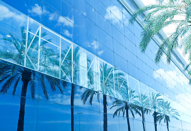 Man captures his reflection in convex traffic safety mirror against backdrop of Walking Street, also known as Red Trail, through his camera. Miami Beach. USA.