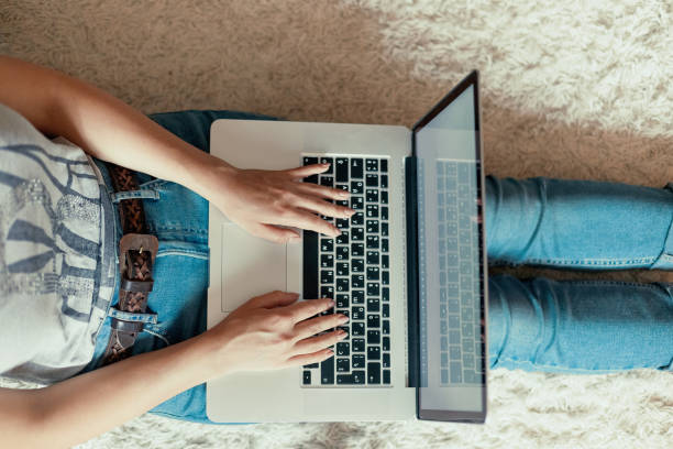 istock Woman working on a laptop. Female using a laptop sitting on floor, searching web, browsing information, having workplace at home. The concept of blogging. Modern technologies. Top view. 1821000462