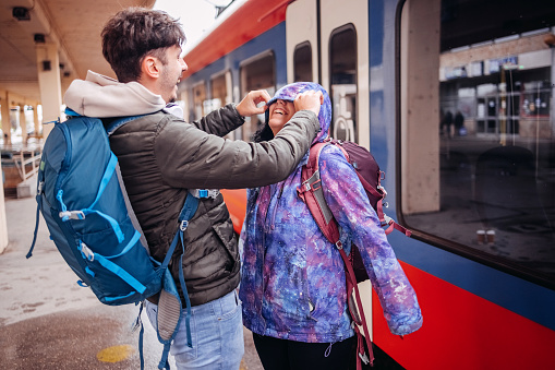 Couple going on vacation from train station carrying backpacks