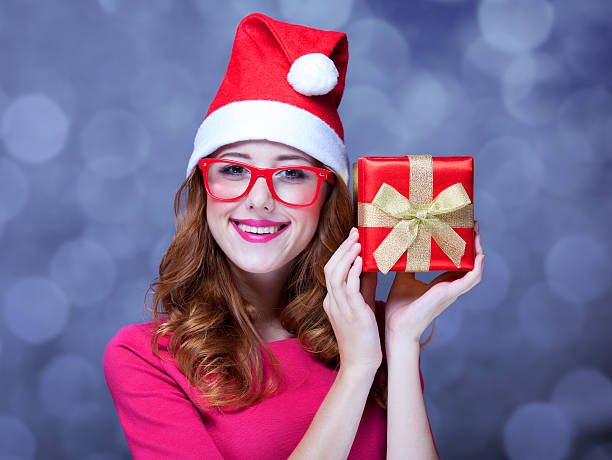 istock Redhead girl in christmas hat with gift. 182102015