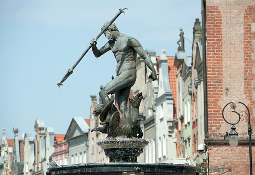 The view of historic 17th century fountain and Gdansk old town houses in a background (Poland).
