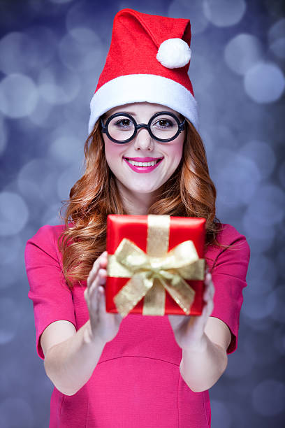 istock Redhead girl in christmas hat with gift. 182102977