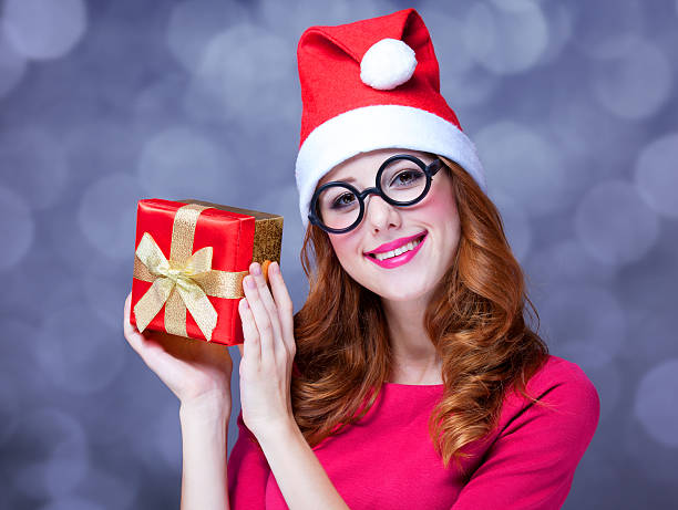 istock Redhead girl in christmas hat with gift. 182103046