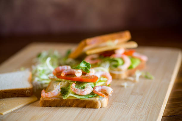 sandwich with lettuce and shrimp on a wooden board