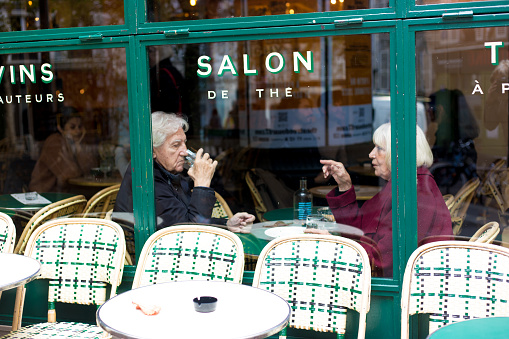 Paris, France: A senior couple chat inside a cafe/tea salon in the 9th arrondissement.