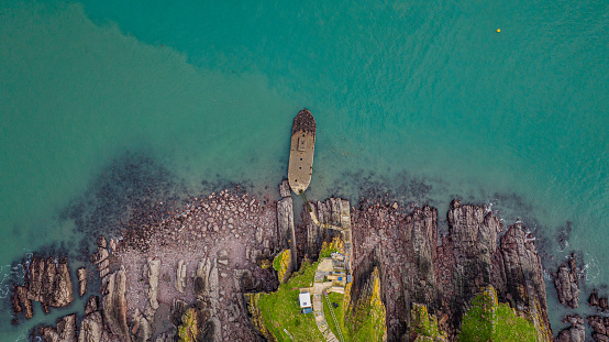 Aerial photo from a drone of the pier at Thorne Island in Milford Haven, Pembrokeshire, Wales, UK. An old concrete barge has been used for access to the island.