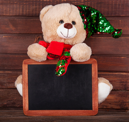 Christmas decoration with teddy bear and blackboard on rustic wooden background