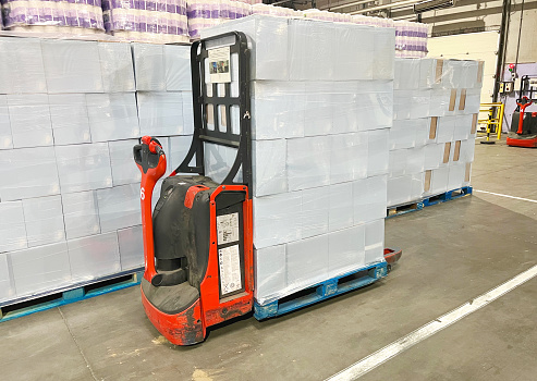 Loading and unloading cargo on pallets using a self-propelled electric cart.