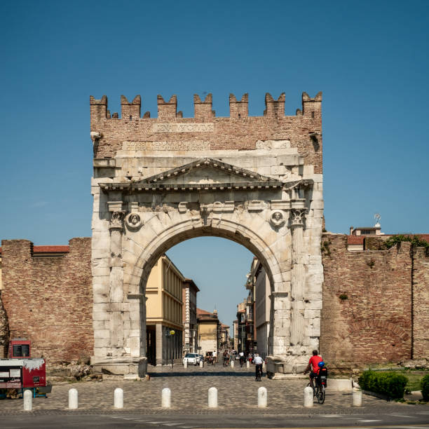 Rimini, Italy - August 02, 2022: The Arch of Augustus is a gate in the former city wall of Rimini, Italy. The arch was dedicated to the Emperor Augustus by the Roman Senate in 27 BC and is one of the oldest Roman arches which survives to this day. It signaled the end of the via Flaminia, which connected the cities of Romagna to Rome, and spans the modern Corso d'Augusto, which led to the beginning of another road, the via Emilia, which ran northwest to Piacenza.