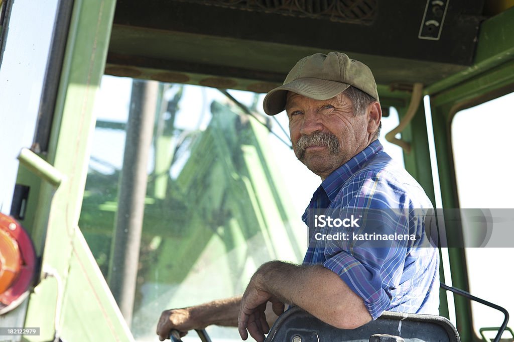 Farmer in his Tractor A candid portrait of a senior male farmer sitting in a green tractor. Farmer Stock Photo