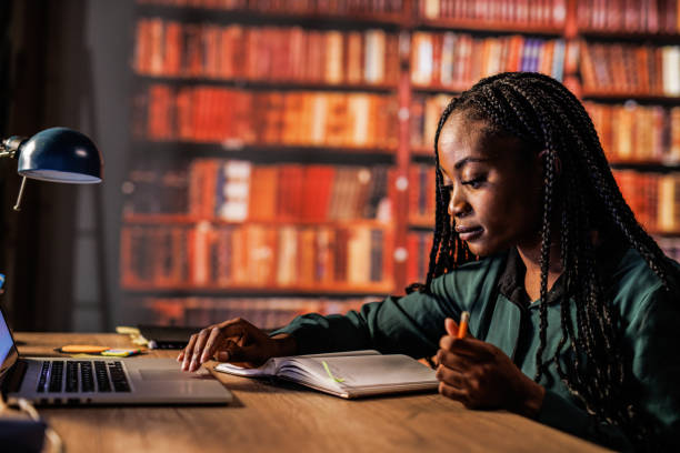 istock Young woman using laptop, writing notes and studying at the library 1821234346