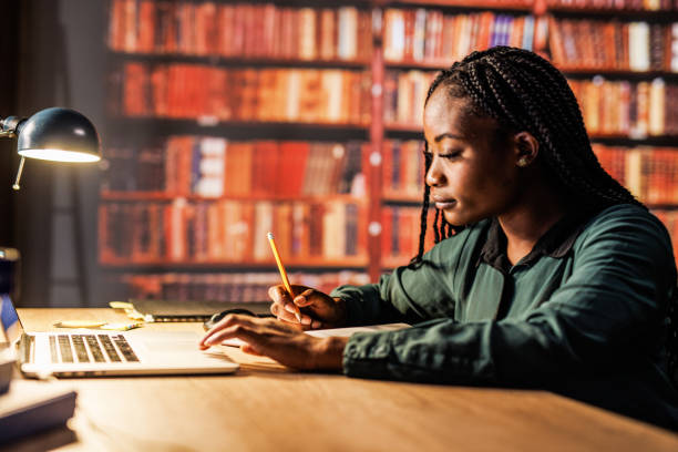 istock Young woman using laptop, writing notes and studying at the library 1821234354