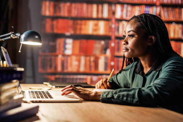 istock Young woman using laptop, writing notes and studying at the library 1821234368