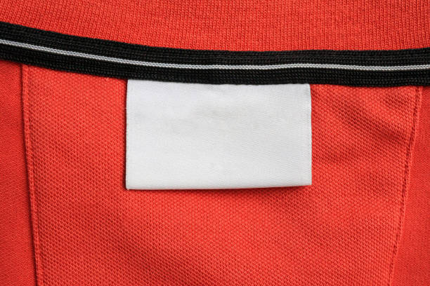 istock Blank white laundry care clothes label on orange shirt fabric texture background 1821242386