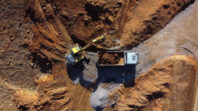 Aerial view of the excavator putting soil in the dump truck