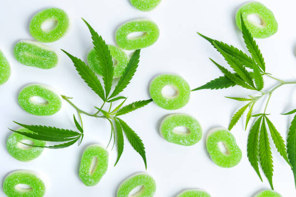 Colored candy gelatin with marijuana leaves on white background Gummy jelly in green and white color with marijuana leaves, over white background. Sweet gummies with CBD, THC oil bud candy stock pictures, royalty-free photos & images