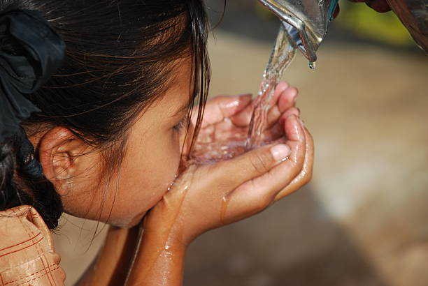 Small dark haired child drinking water using her hands Rural girl Drinking water... hyderabad india photos stock pictures, royalty-free photos & images