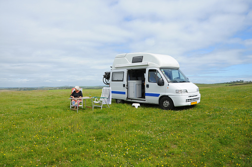 My campervan on an English meadow (Cornwall) with my wife sitting at table.