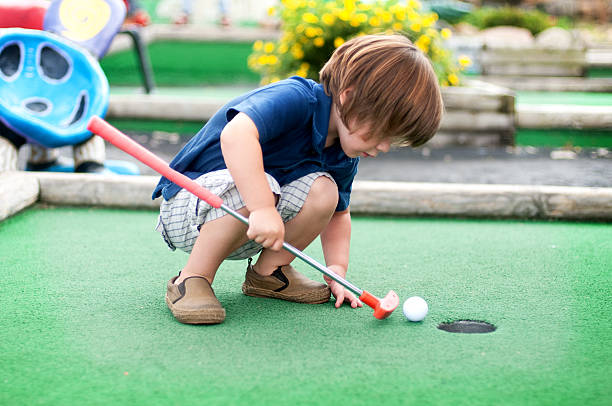 Mini Golf Little boy playing mini golf. putting stock pictures, royalty-free photos & images