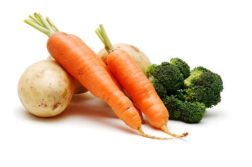 Carrots, onions, potatoes, peppers, greens spread out next to each other.  Fresh, clean and colorful raw vegetables