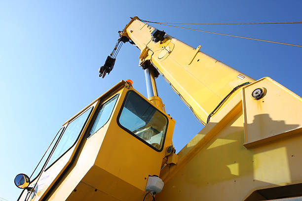 Angled view of yellow mobile construction crane against sky Large mobile construction crane shot close-up in late afternoon sun. mobile crane stock pictures, royalty-free photos & images